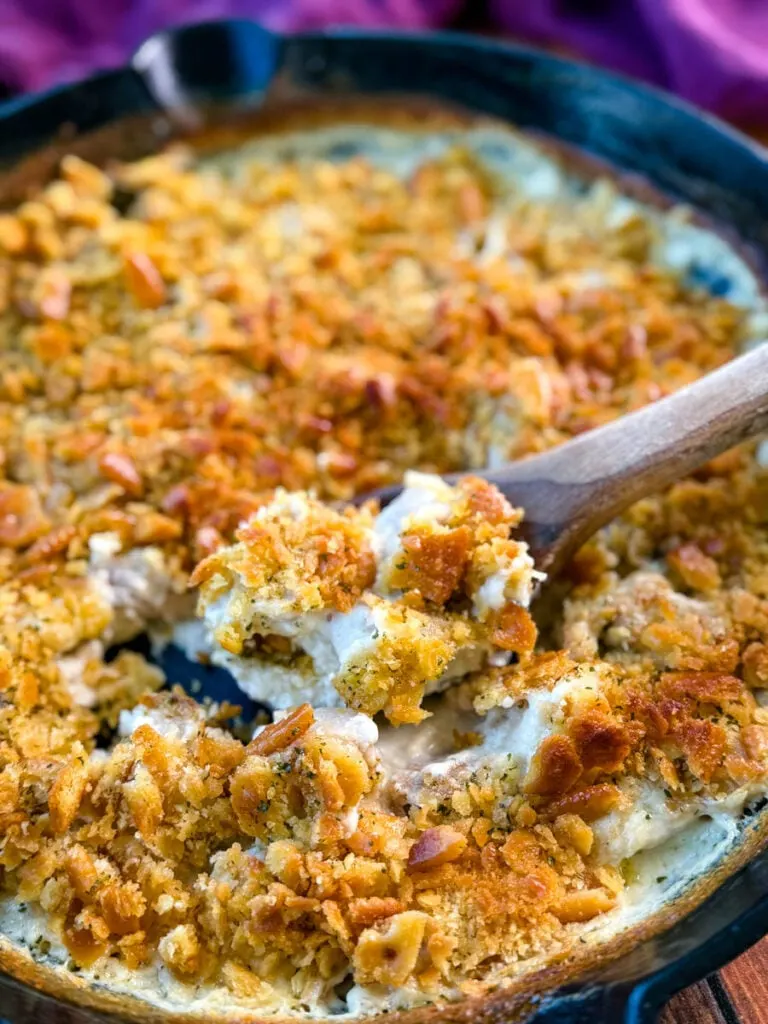 million dollar chicken casserole in a cast iron skillet with a wooden spoon