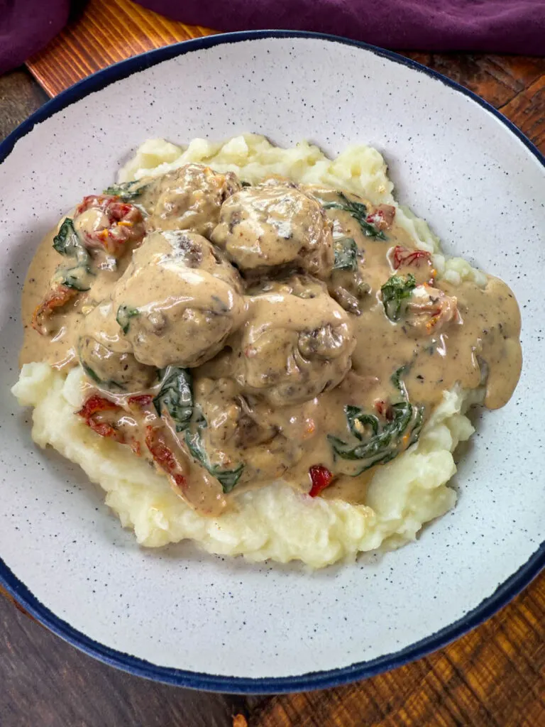 marry me meatballs drizzled in Tuscan cream sauce with mashed potatoes in a white bowl