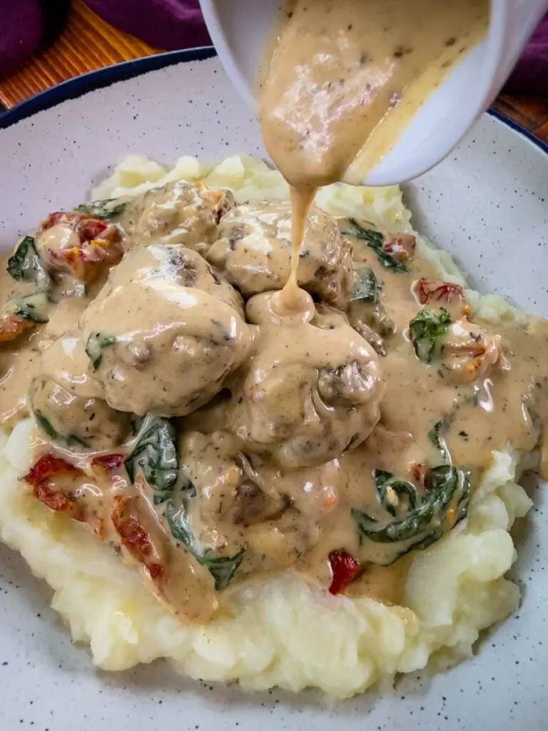 marry me meatballs drizzled in Tuscan cream sauce with mashed potatoes in a white bowl