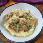 marry me meatballs drizzled in Tuscan cream sauce with mashed potatoes in a white bowl