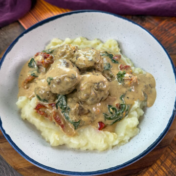 marry me meatballs drizzled in Tuscan cream sauce with mashed potatoes in a white bowl