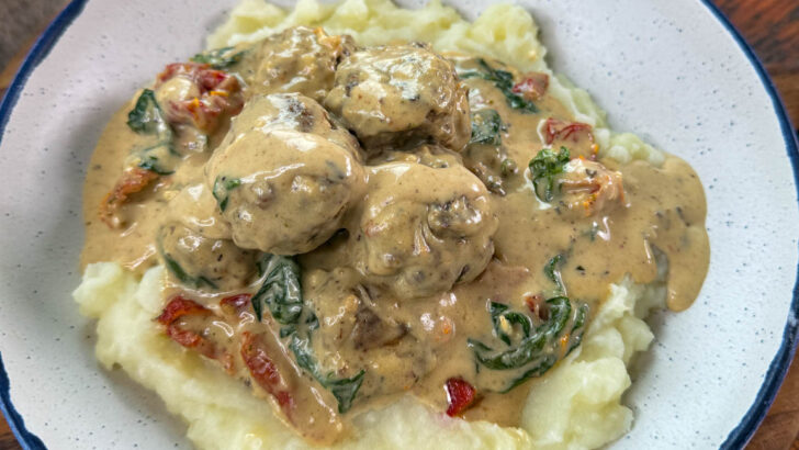 marry me meatballs drizzled in Tuscan cream sauce with mashed potatoes in a white bowl