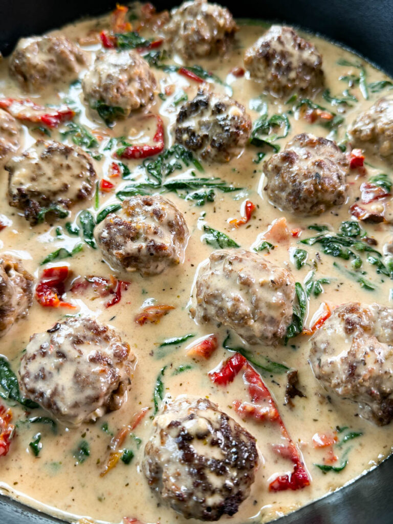 marry me meatballs drizzled in Tuscan cream sauce with mashed potatoes in a skillet