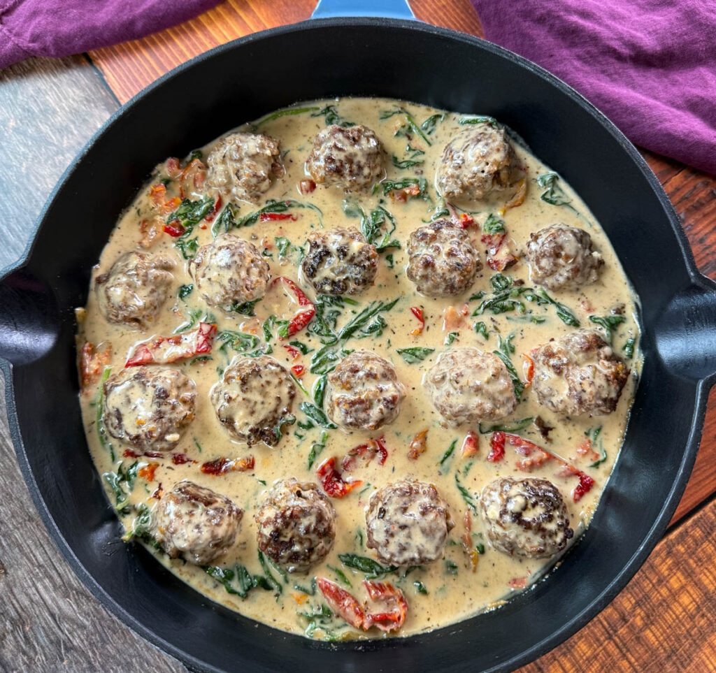 marry me meatballs drizzled in Tuscan cream sauce with mashed potatoes in a skillet