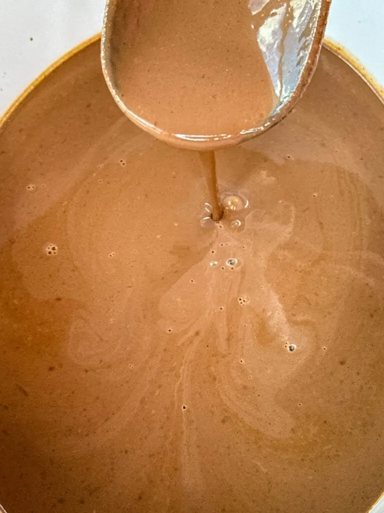 hot chocolate in a Crockpot slow cooker with a wooden spoon