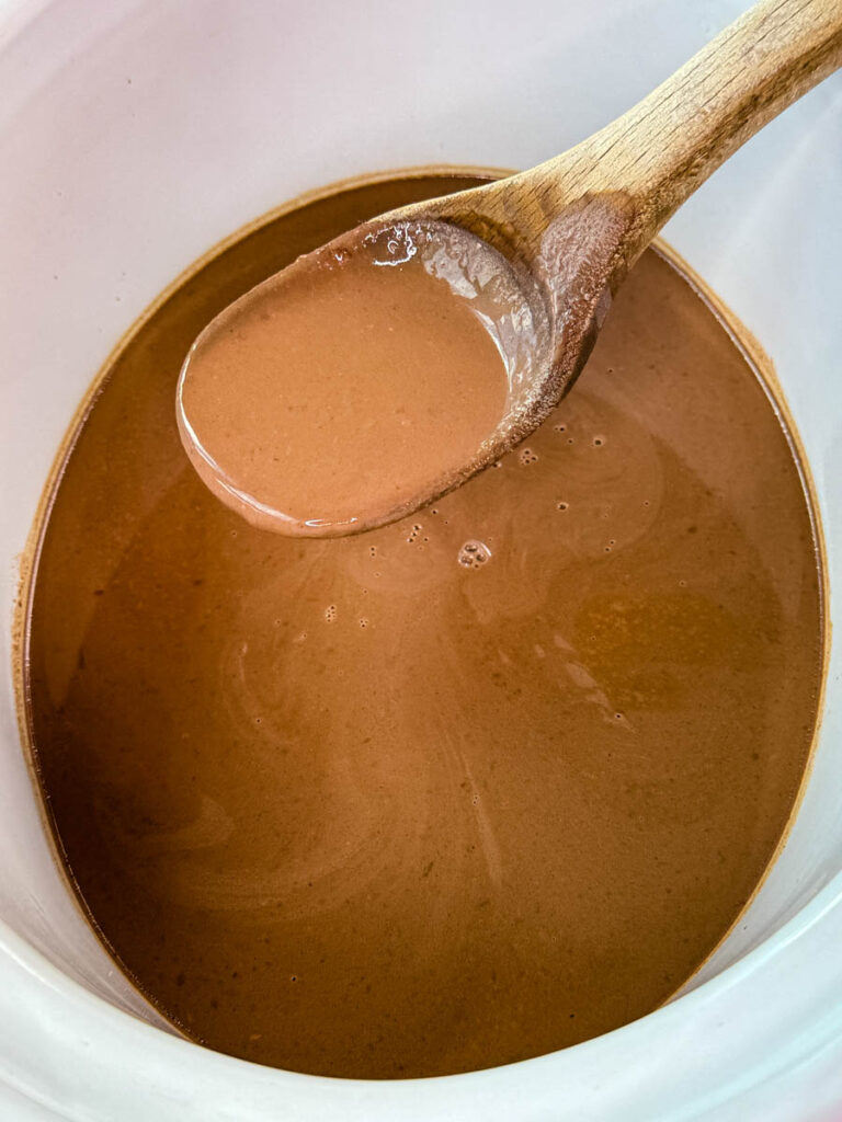 hot chocolate in a Crockpot slow cooker with a wooden spoon