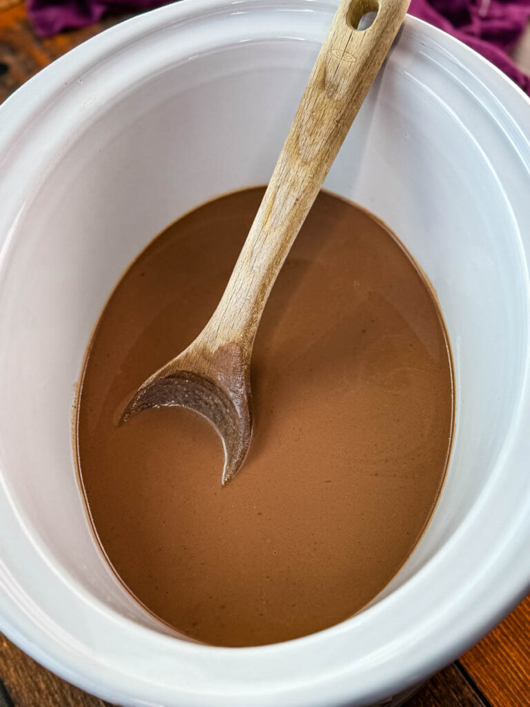 hot chocolate in a Crockpot slow cooker with a wooden spoon