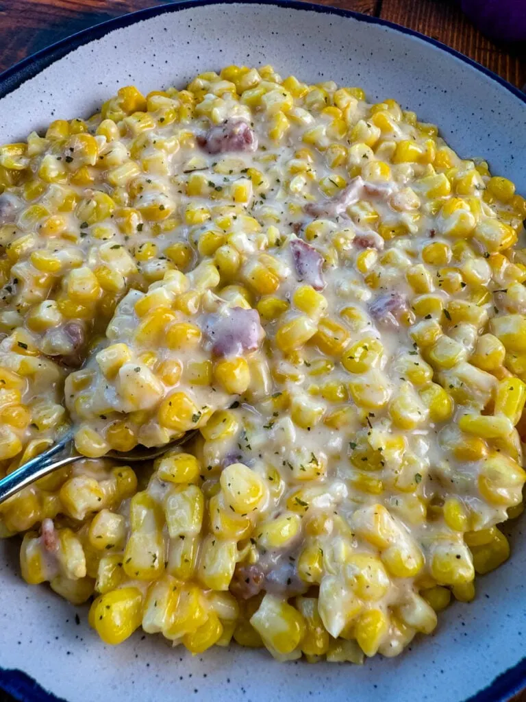 southern soul food creamed corn in a white bowl with a spoon