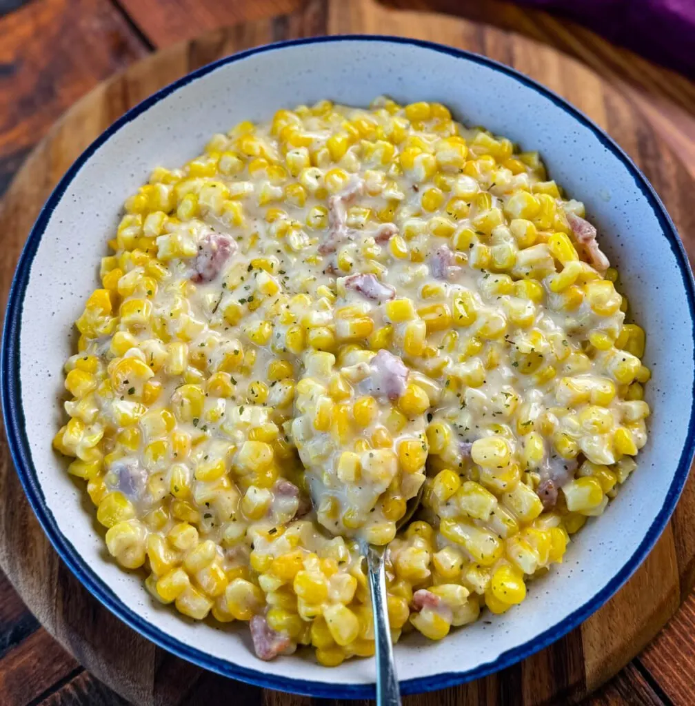 southern soul food creamed corn in a white bowl with a spoon