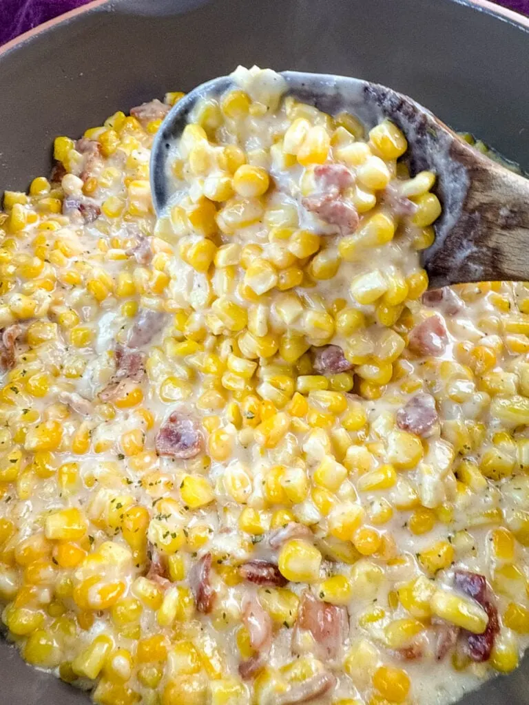 southern soul food creamed corn in a skillet with a wooden spoon