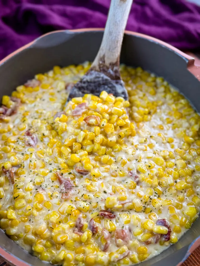 southern soul food creamed corn in a skillet with a wooden spoon