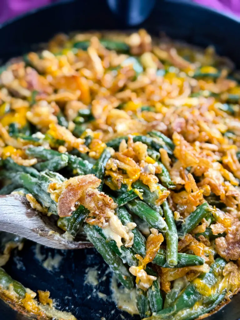 green bean casserole without canned cream of mushroom soup in a skillet with a wooden spoon