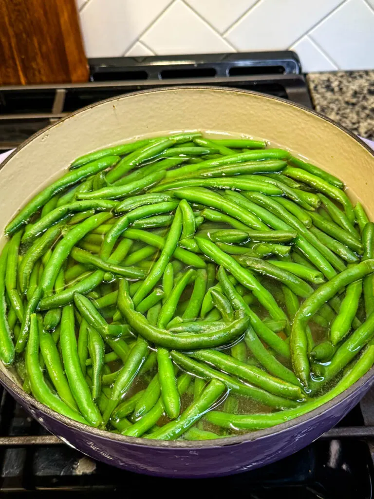 blanched green beans in boiling water in a Dutch oven on the stove