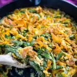 green bean casserole without canned cream of mushroom soup in a skillet with a wooden spoon