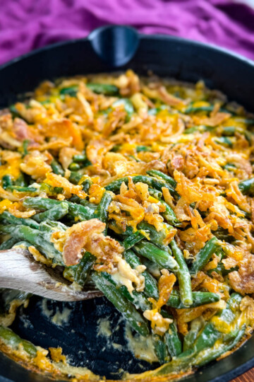 green bean casserole without canned cream of mushroom soup in a skillet with a wooden spoon