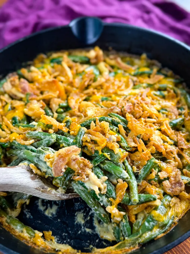 green bean casserole without canned cream of mushroom soup in a skillet with a wooden spoon