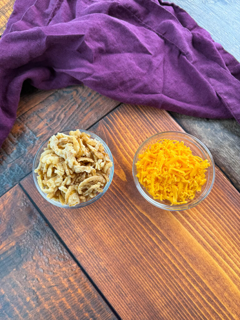 fried onions and grated cheddar cheese in separate glass bowls