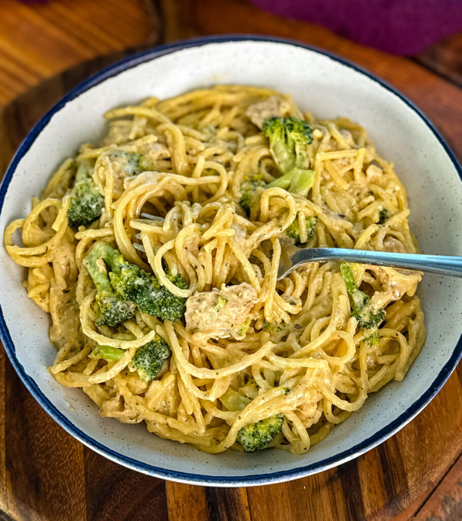 creamy chicken broccoli Alfredo in a white bowl with a fork and a piece of toasted bread