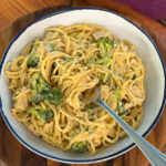 creamy chicken broccoli Alfredo in a white bowl with a fork