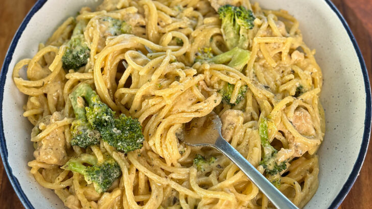 creamy chicken broccoli Alfredo in a white bowl with a fork