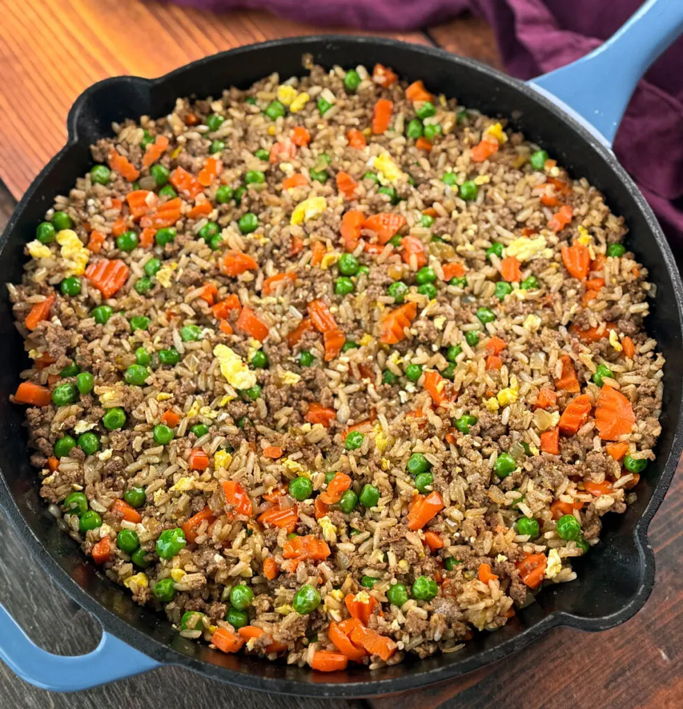 beef fried rice in a skillet with eggs, peas, and carrots