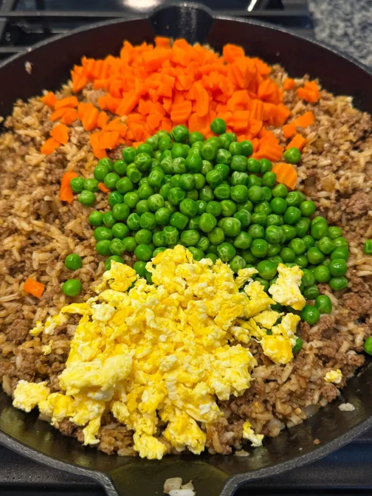 beef fried rice in a skillet with eggs, peas, and carrots