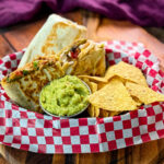 high protein chicken burritos, guacamole, and chips in a bowl