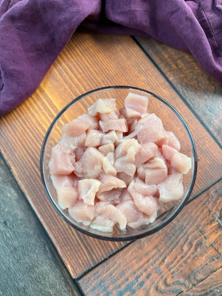 raw, boneless, skinless diced chicken breasts in a glass bowl