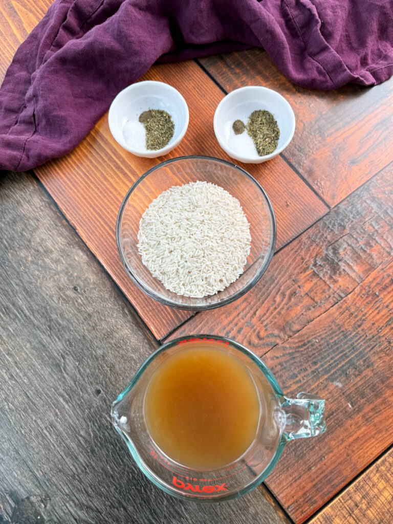 Italian Seasoning, dry white rice, and chicken broth in separate glass bowls