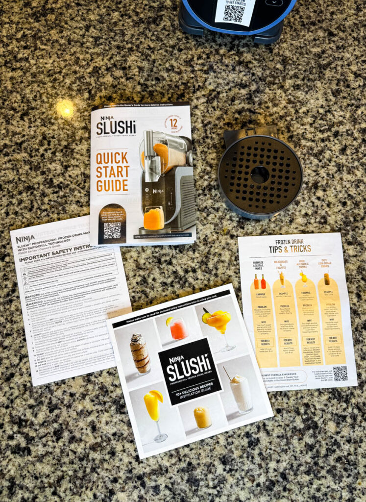 Instruction Manuals and Recipe Booklet for the Ninja SLUSHi Machine – A flat lay of the included documentation, showing tips for making frozen drinks, safety instructions, and setup guidance.