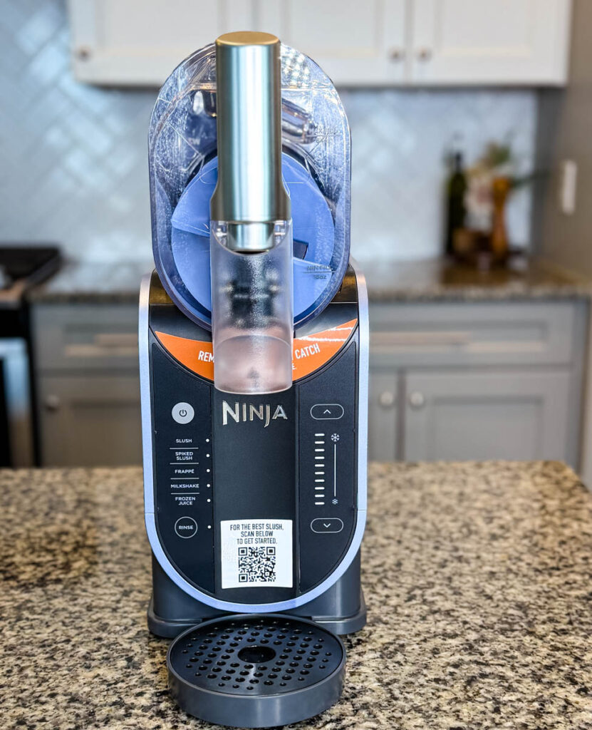 Empty Ninja SLUSHi Machine Side View – The chamber is empty, revealing the rotating auger inside. The machine is placed on a kitchen counter with a backsplash.