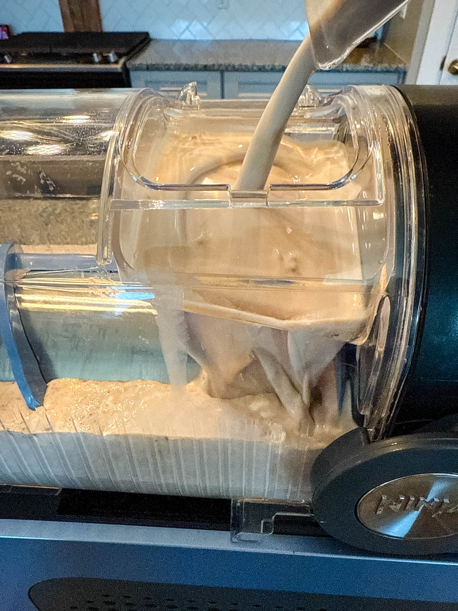 A Ninja slushie machine in action, with the homemade Frosty mixture being poured into the machine.